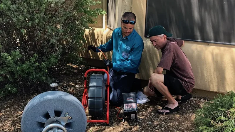 Elite Rooter technician with sewer camera equipment beside a homeowner