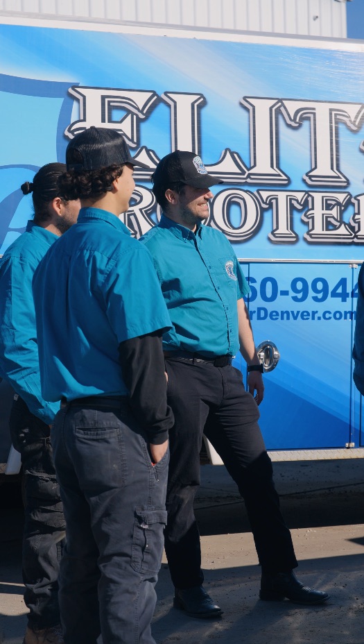 Elite Rooter plumbers talking together beside a service van
