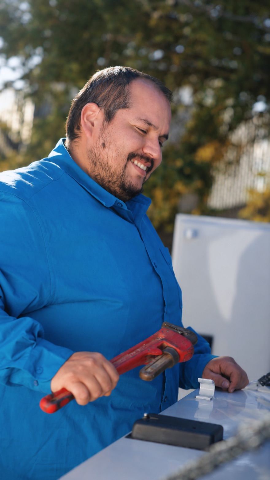 Elite Rooter plumber with a pipe wrench at the service truck
