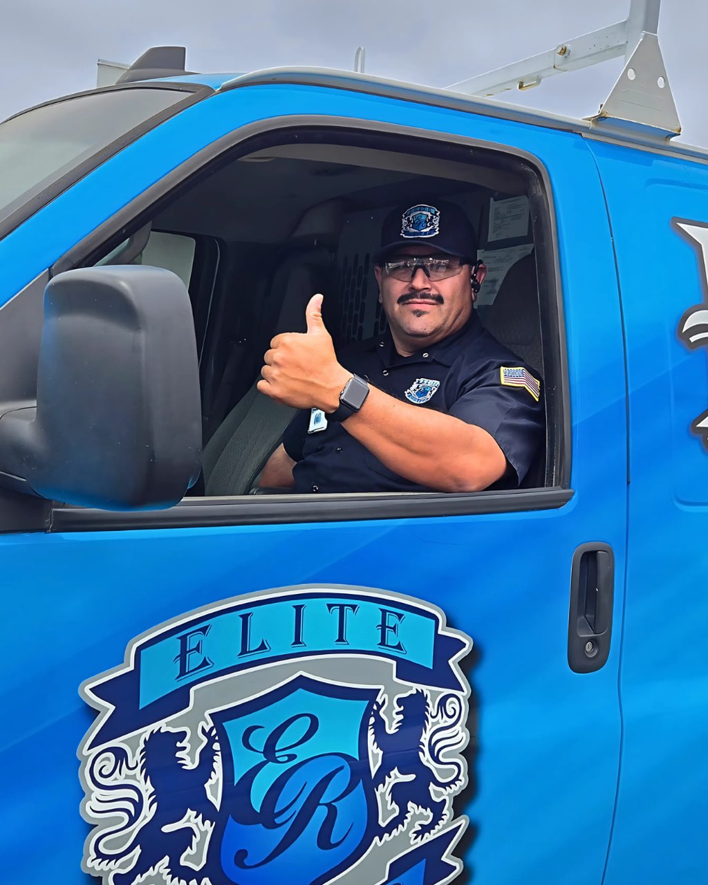 Elite Rooter technician giving a thumbs-up from a branded service van