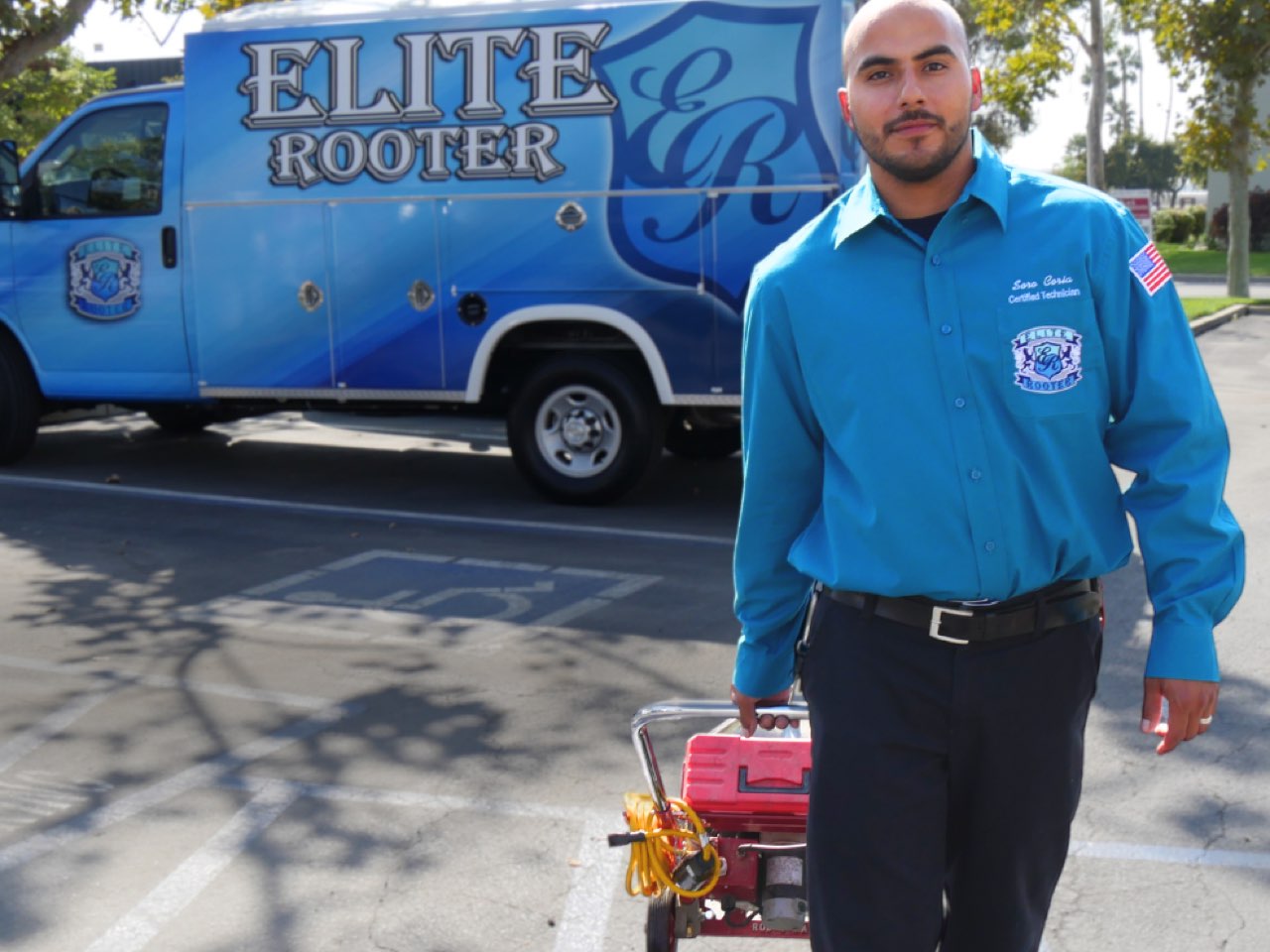 Elite Rooter technician standing beside a branded service vehicle