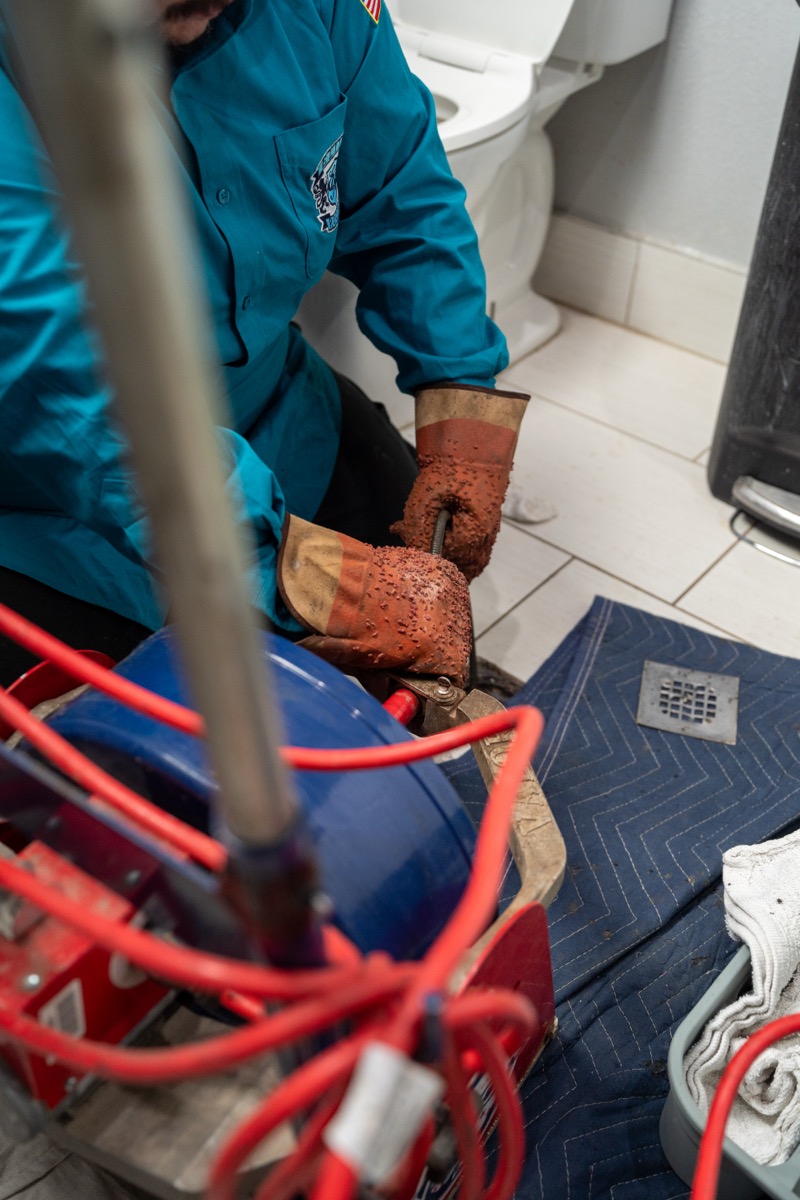 Elite Rooter technician using drain equipment in a bathroom