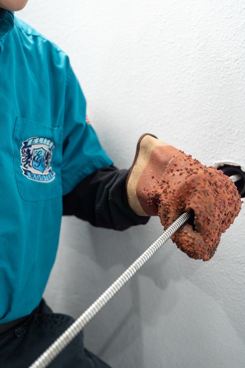Elite Rooter technician guiding professional drain equipment