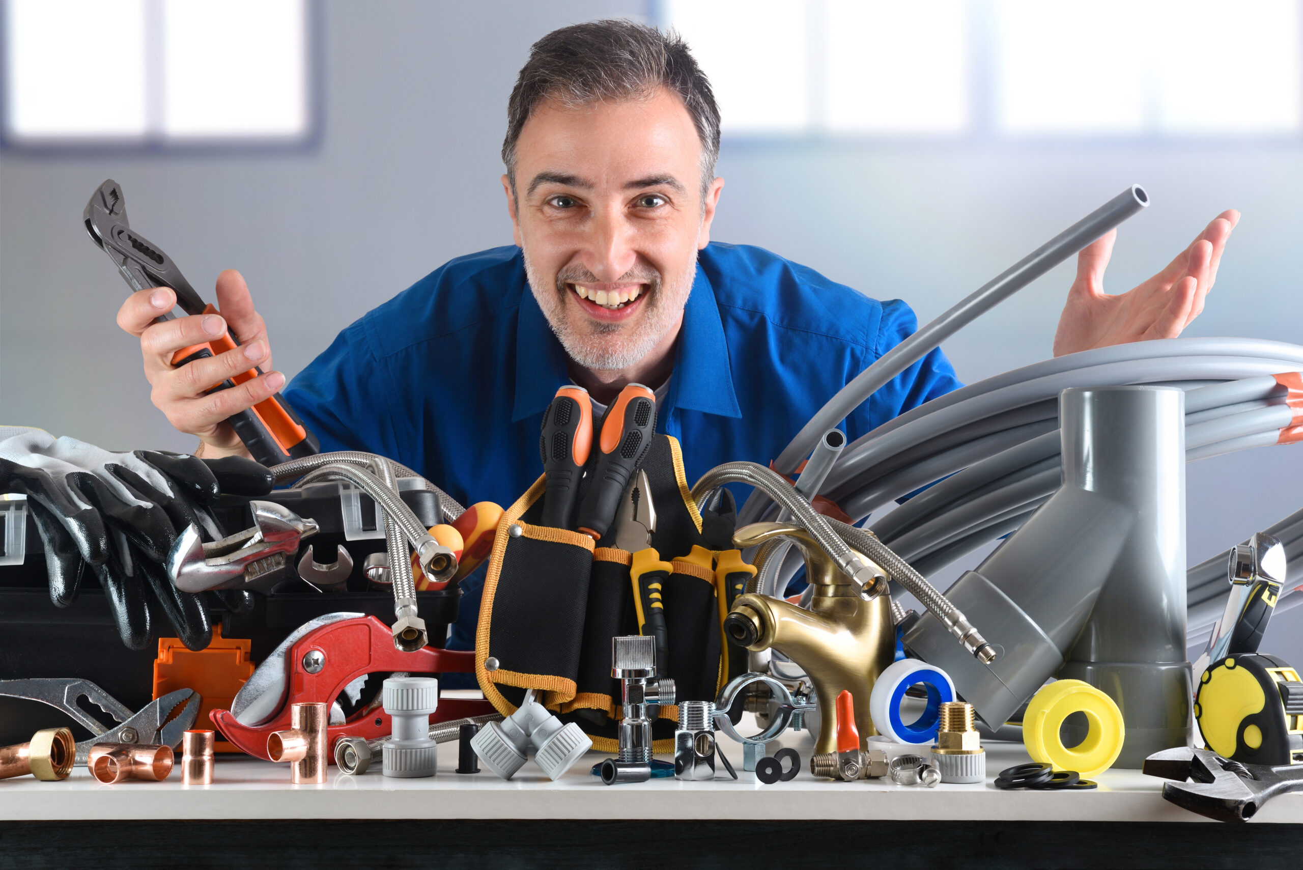 Plumbing material and smiling plumber behind in industrial warehouse