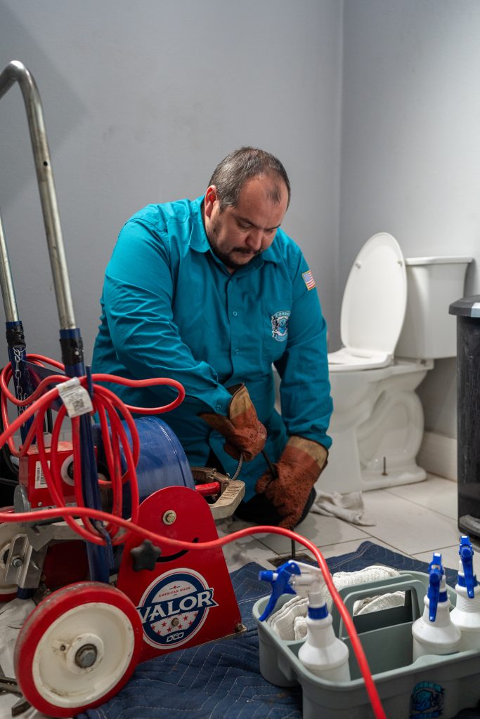 Elite Rooter plumber using a Valor drain machine in a bathroom