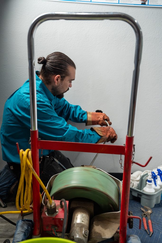 Elite Rooter technician operating a drain snake machine